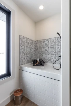 Built-in dog wash station with tiled backsplash and handheld shower in custom RTM home in Alberta and Saskatchewan