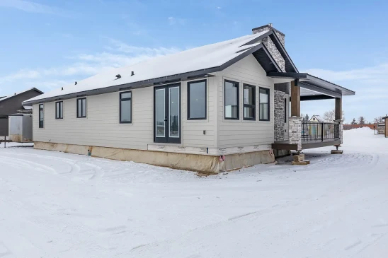 Side view of ready-to-move RTM bungalow with large windows and stone chimney in Alberta and Saskatchewan