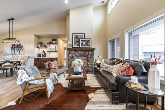 Open concept living room in a custom Ready to Move home with vaulted ceilings, stone fireplace, and large windows.