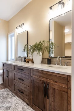 Double vanity in a custom RTM home featuring wood cabinetry, quartz countertops, and modern fixtures.