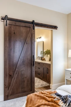 Rustic barn door leading to a spacious primary ensuite in a custom RTM home.
