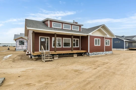 Angled front view of a custom RTM home featuring a covered porch, modern windows, and quality exterior finishes.