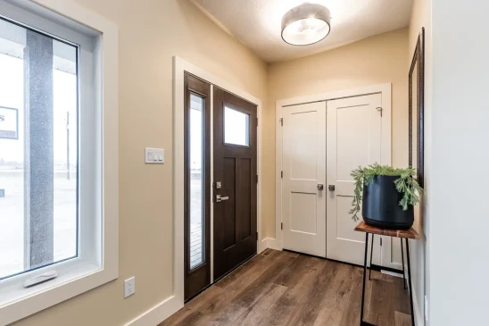 Bright entryway of a custom RTM home featuring a modern front door, spacious foyer, and durable flooring.