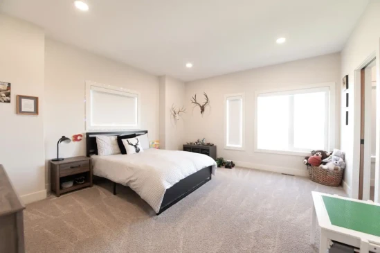 Bright secondary bedroom with large windows, plush carpet, and spacious layout.