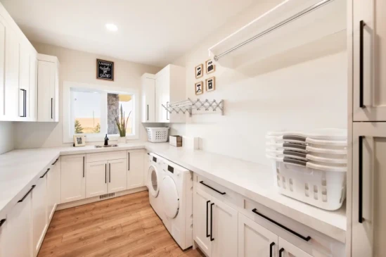 Functional laundry room with extensive cabinetry, folding counters, utility sink, and built in storage.