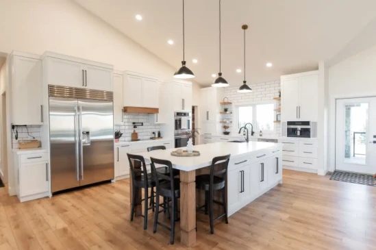 Spacious custom kitchen with quartz island, premium stainless steel appliances, white shaker cabinetry, and modern pendant lighting.