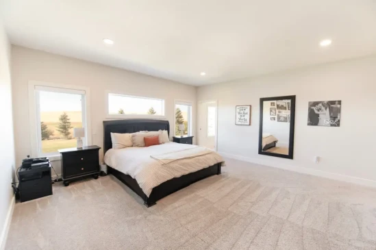 Spacious primary bedroom with large windows, plush carpeting, and scenic countryside views.