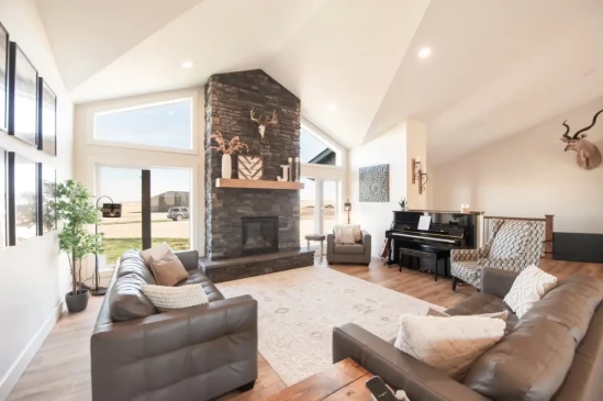 Luxury living room with vaulted ceilings, floor to ceiling stone fireplace, and expansive windows.