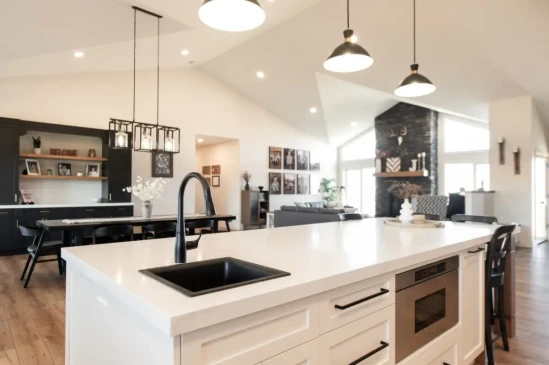 Bright open concept kitchen with quartz island, black fixtures, vaulted ceilings, and spacious living area.