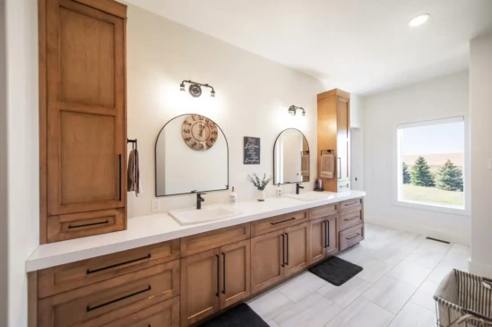 Luxury ensuite bathroom with double vanity, custom wood cabinetry, quartz countertops, and modern fixtures.