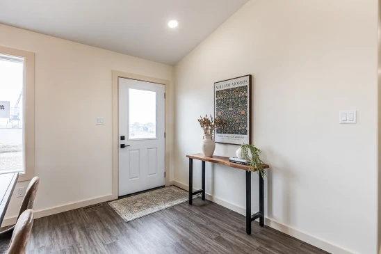 Bright RTM home entryway with wood console table, vinyl plank flooring and modern front door in Alberta and Saskatchewan