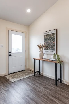 Bright RTM home entryway with wood console table, vinyl plank flooring and modern front door in Alberta and Saskatchewan