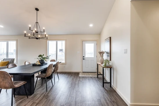 Open concept dining area in RTM home with modern chandelier and wide plank flooring in Alberta and Saskatchewan