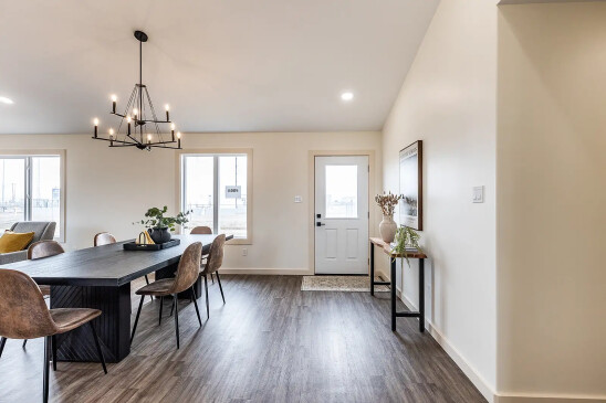 Open concept dining area in RTM home with modern chandelier and wide plank flooring in Alberta and Saskatchewan