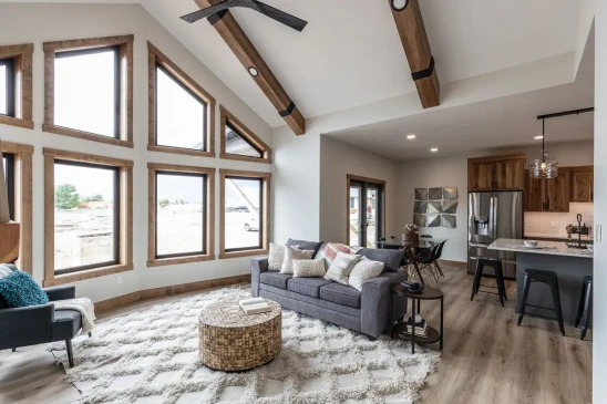 Bright open concept RTM home living area with vaulted ceiling, oversized windows and stone fireplace in Alberta and Saskatchewan