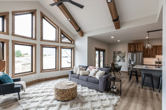 Bright open concept RTM home living area with vaulted ceiling, oversized windows and stone fireplace in Alberta and Saskatchewan