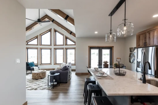 Open concept RTM home interior with quartz island, rustic wood cabinetry and vaulted ceiling living room in Alberta and Saskatchewan