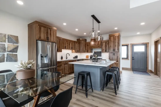Open concept RTM home kitchen and dining area with island seating and stainless steel fridge in Alberta and Saskatchewan