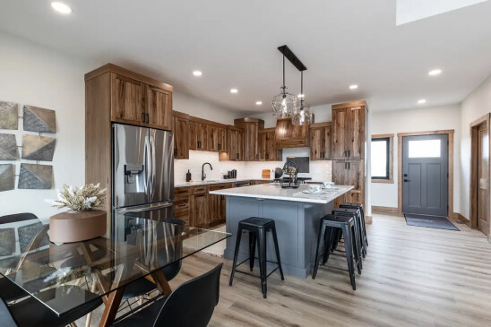 Open concept RTM home kitchen and dining area with island seating and stainless steel fridge in Alberta and Saskatchewan