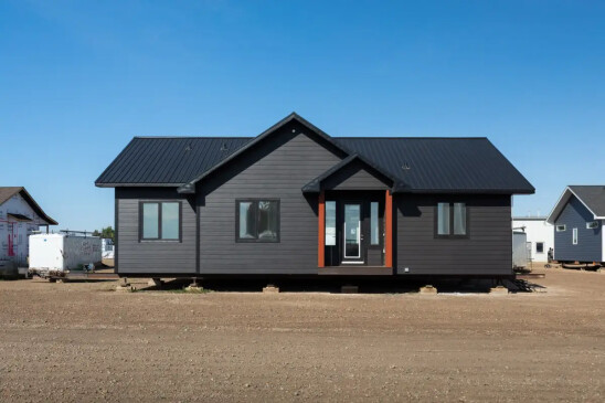 Modern RTM home with black exterior siding, metal roof, and covered front entry built by Jade Homes.
