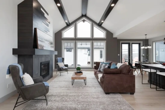 Spacious living room in a modern RTM home featuring vaulted ceilings, large windows, and a statement fireplace.