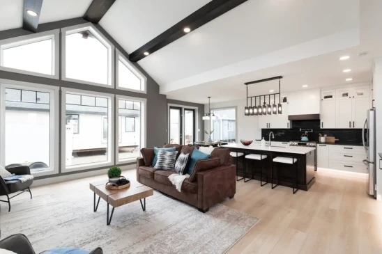Open concept living room and kitchen in a custom RTM home featuring vaulted ceilings and oversized windows.
