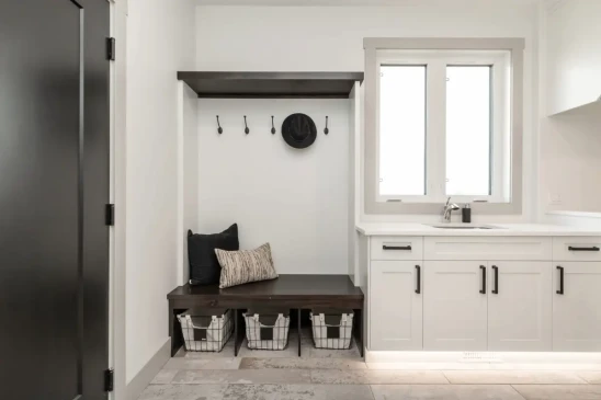 Custom mudroom with built in bench, storage cubbies, coat hooks, and integrated laundry sink.