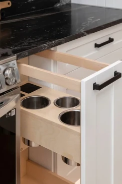 Custom kitchen pull out waste and recycling drawer with built in storage for convenient organization.