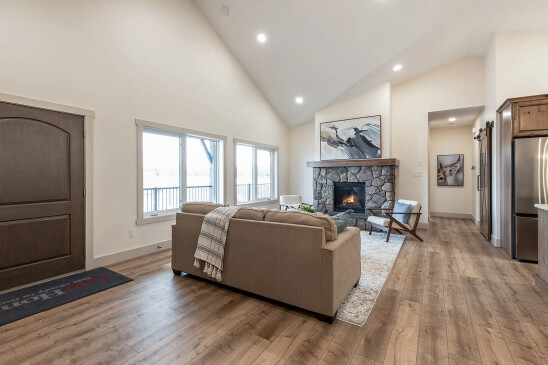 Open concept RTM living room with vaulted ceiling, stone fireplace and large picture windows in Alberta and Saskatchewan